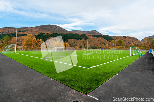 Image of green soccer field with mountains and autumn colors