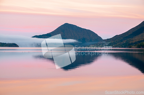 Image of mountains reflected in the sea in pink light