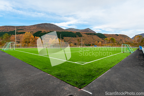 Image of green soccer field with mountains and autumn colors