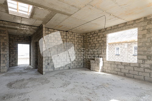 Image of Construction of an individual residential building, view of a spacious room with a large window opening and a corridor leading to the front door