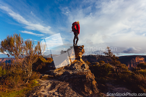 Image of Woman hiker standing on top of rock precipice with grand views