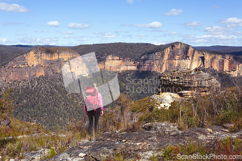 Image of Female taking in magnificent vistas of sheer sandstone cliffs ac