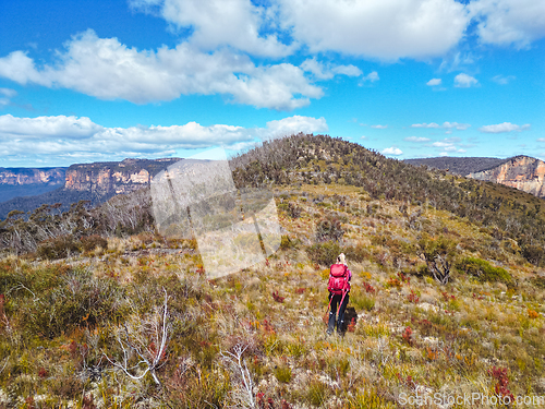 Image of Woman hiking across an exposed hill high in the upper Blue Mount