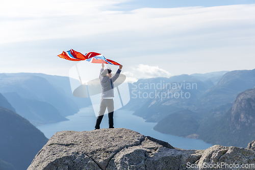 Image of Woman with a waving flag of Norway on the background of nature