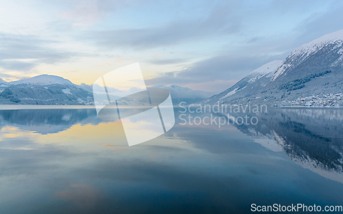 Image of reflection in fjord with sun behind clouds