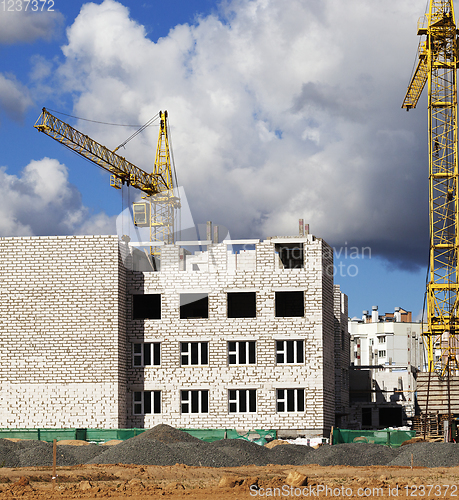 Image of construction cranes and brick building