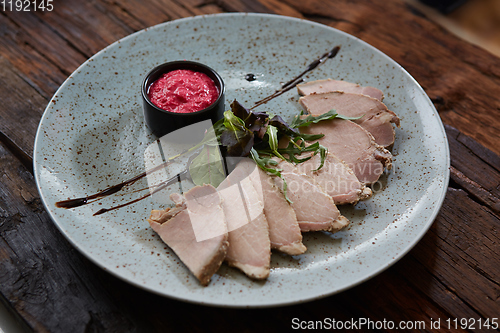 Image of Sliced cold baked pork with herbs on blue plate