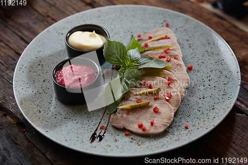 Image of Sliced cold baked pork with herbs on blue plate