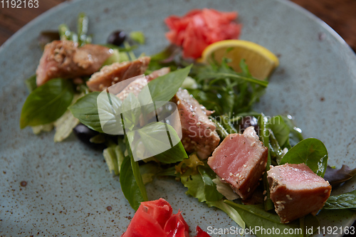 Image of beautiful food: steak tuna in sesame, lime and fresh salad close-up on a plate on the table.