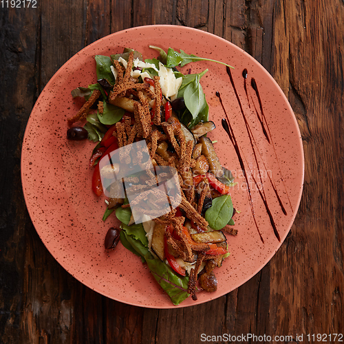 Image of Salad baked eggplant with green onions, croutons and tomatoes on wooden background.