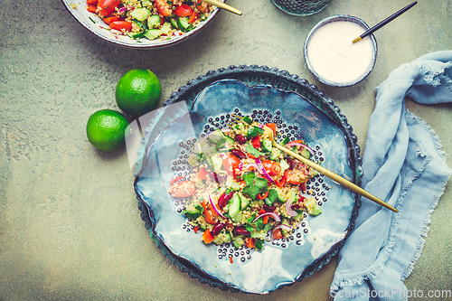 Image of Healthy quinoa black bean salad with fresh tomatoes, cucumbers, onion and cilantro