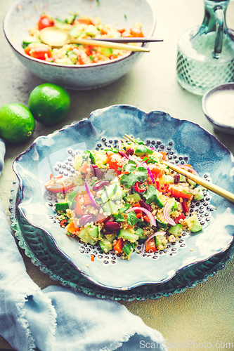 Image of Healthy quinoa black bean salad with fresh tomatoes, cucumbers, onion and cilantro