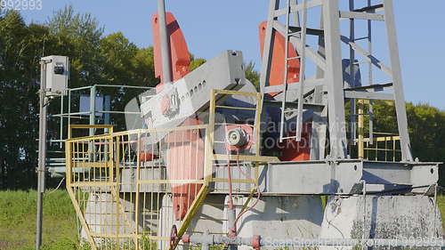 Image of Operating oil and gas well in oil field, profiled against the blue sky