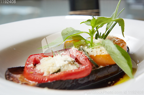 Image of Baked eggplant with parmesan cheese, tomatoes and basil.