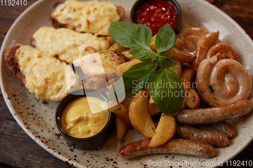 Image of Grilled assorted sausages with French fries, bruschettes with cheese and sauces.