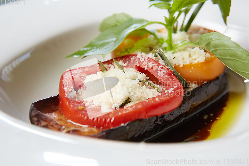 Image of Baked eggplant with parmesan cheese, tomatoes and basil.