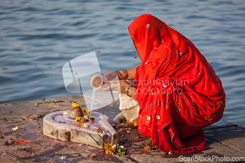 Image of Indian woman performs morning pooja on holy river Narmada ghats