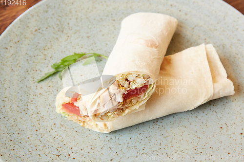 Image of Lavash roll with chicken and vegetables close up on a plate. horizontal