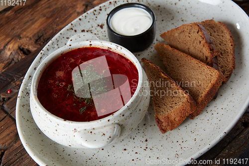 Image of Traditional Ukrainian Russian borscht with white beans on the bowl. Plate of red beet root soup borsch on black rustick table. Beetroot soup Top view. Traditional Ukraine food cuisine