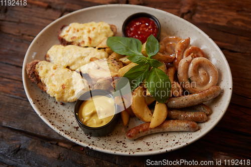 Image of Grilled assorted sausages with French fries, bruschettes with cheese and sauces.