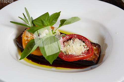 Image of Baked eggplant with parmesan cheese, tomatoes and basil.