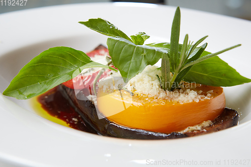 Image of Baked eggplant with parmesan cheese, tomatoes and basil.