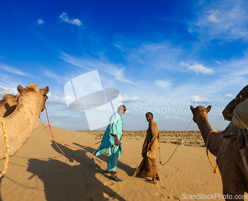 Image of Two cameleers (camel drivers) with camels in dunes of Thar deser