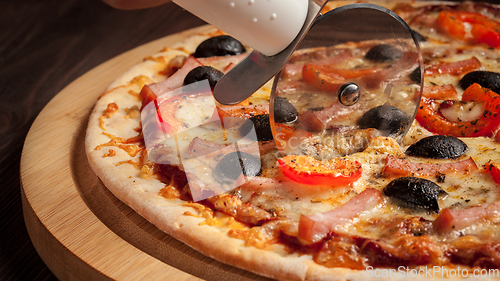 Image of Pizza cutter wheel slicing ham pizza