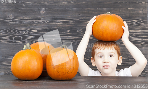 Image of A red-haired boy with red pumpkins