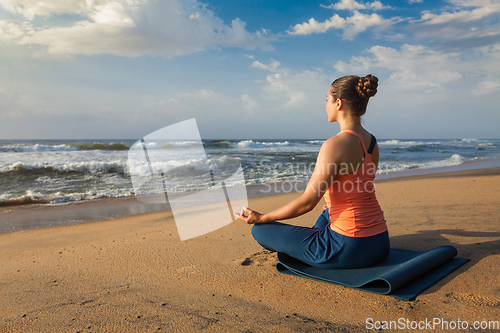 Image of Woman doing yoga Lotus pose oudoors at beach