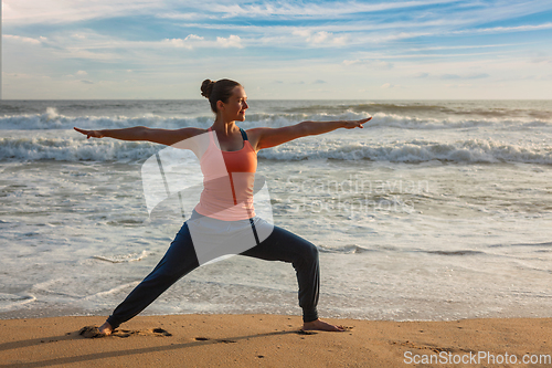 Image of Woman doing yoga asana Virabhadrasana 1 Warrior Pose on beach on