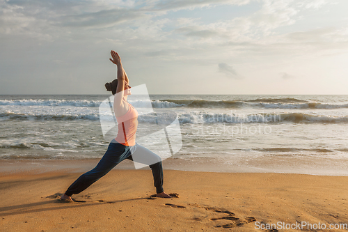 Image of Woman doing yoga asana Virabhadrasana 1 Warrior Pose on beach on