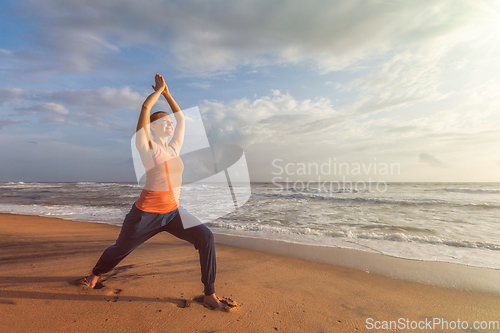 Image of Woman doing yoga asana Virabhadrasana 1 Warrior Pose on beach on