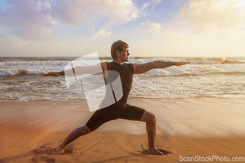 Image of Man doing yoga asana Virabhadrasana 1 Warrior Pose on beach