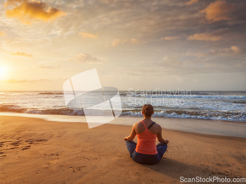 Image of Young sporty fit woman doing yoga oudoors at beach