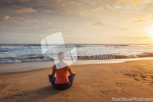 Image of Woman doing yoga Lotus pose oudoors at beach