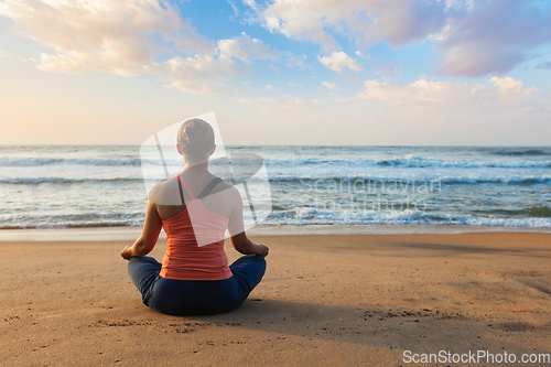 Image of Young sporty fit woman doing yoga oudoors at beach