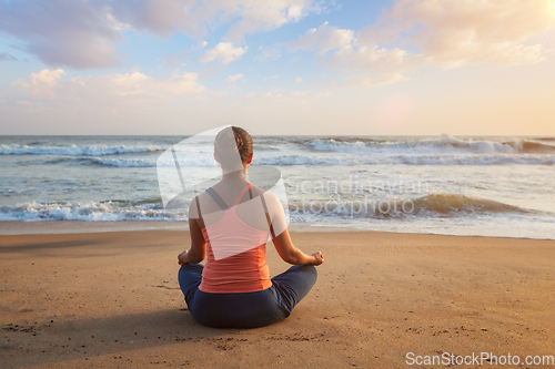Image of Woman doing yoga Lotus pose oudoors at beach