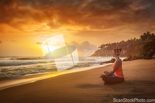 Image of Young sporty fit woman doing yoga oudoors at beach