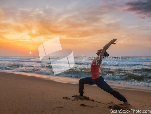 Image of Woman doing yoga asana Virabhadrasana 1 Warrior Pose on beach on