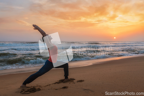 Image of Woman doing yoga asana Virabhadrasana 1 Warrior Pose on beach on