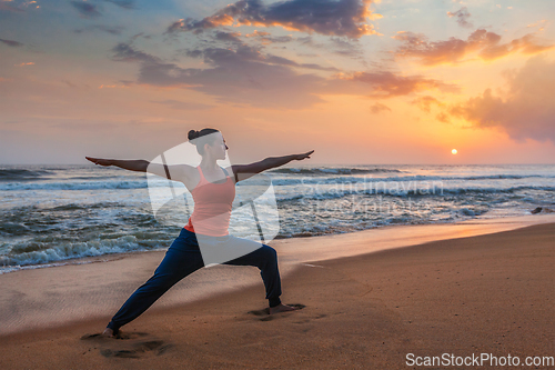 Image of Woman doing yoga asana Virabhadrasana 1 Warrior Pose on beach on