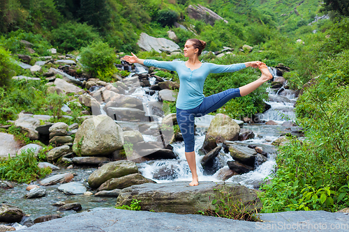 Image of Woman doing Ashtanga Vinyasa Yoga asana outdoors at waterfall