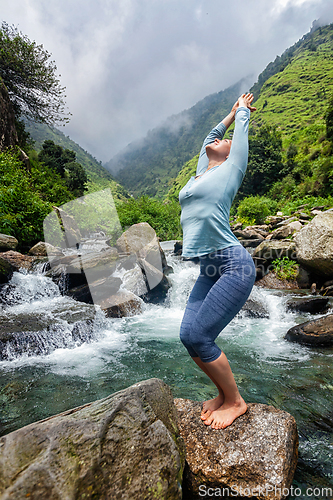 Image of Sorty fit woman doing yoga asana at waterfall