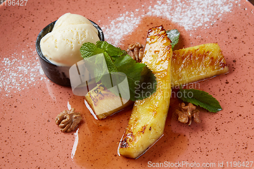 Image of Grilled pineapple with scoops of vanilla ice cream.