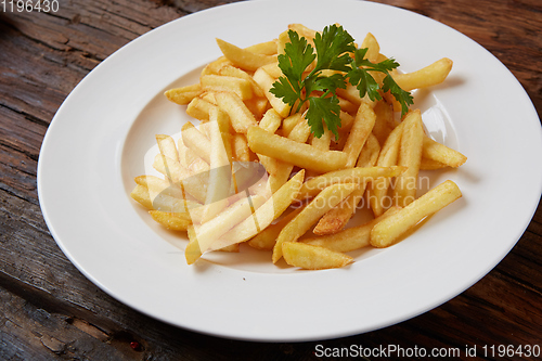 Image of French fries in a bowl on a wooden background.