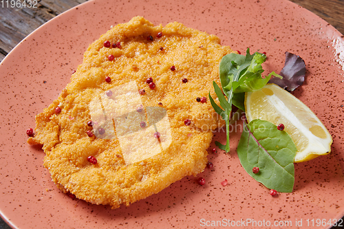 Image of Chicken schnitzel on plate over wooden background, Top view