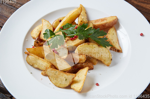 Image of Homemade roasted potato with parsley on rustic background.