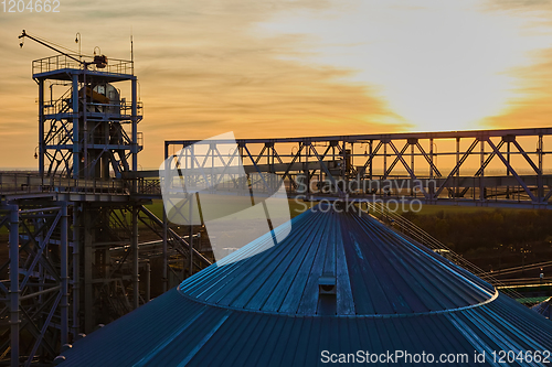 Image of grain silo and dryer at night with pile of grain.