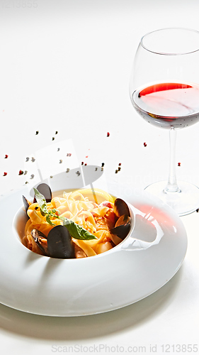 Image of The cooked mussels and pasta with wine glass.